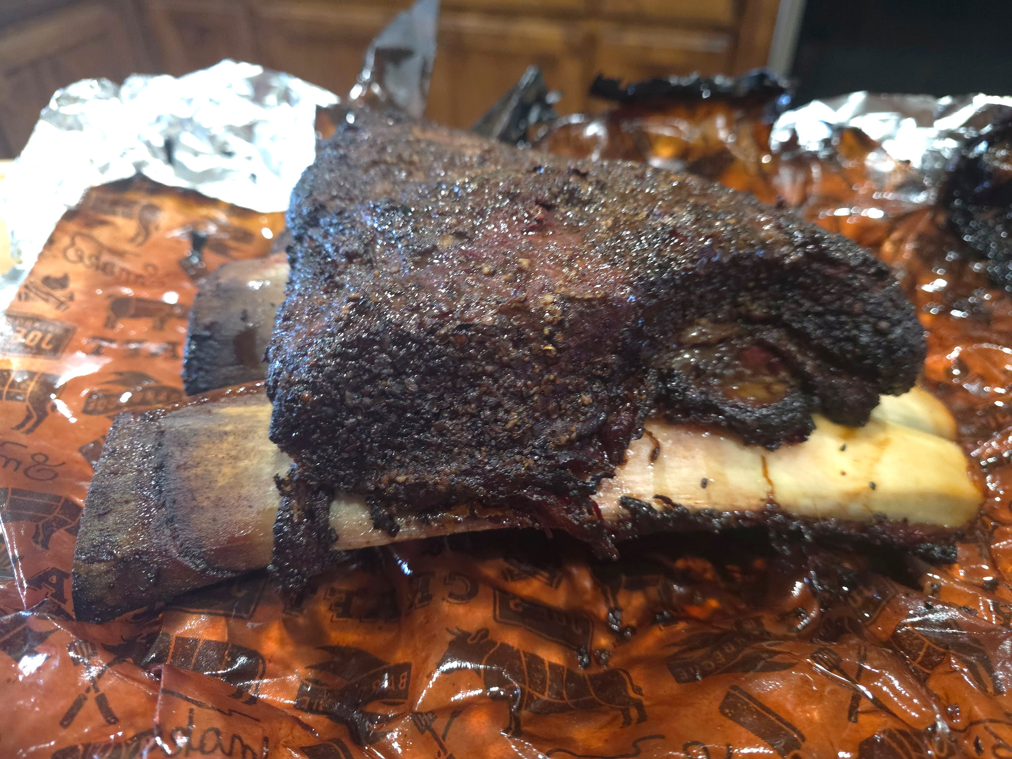Side view of a slow-smoked beef rib with a dark, seasoned bark.