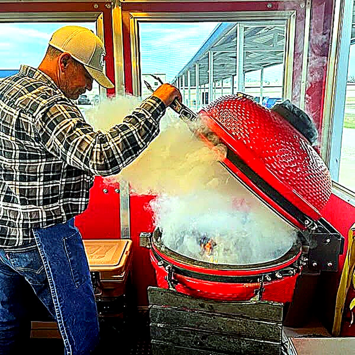 A smoker lid opening with smoke rising in the Red Cooler BBQ trailer.