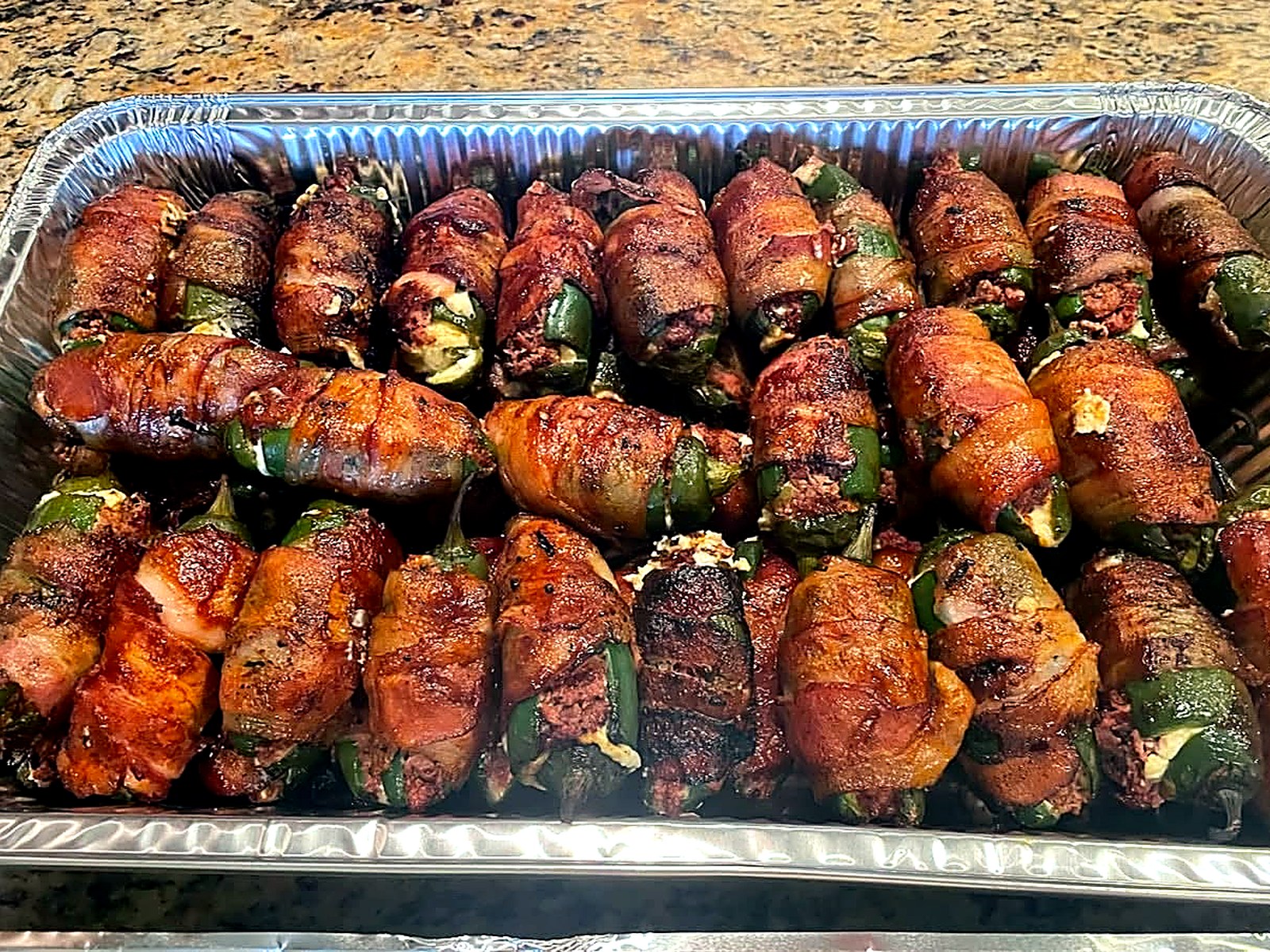 Bacon-wrapped jalapeño poppers, called Texas Twinkies, arranged in a tray.